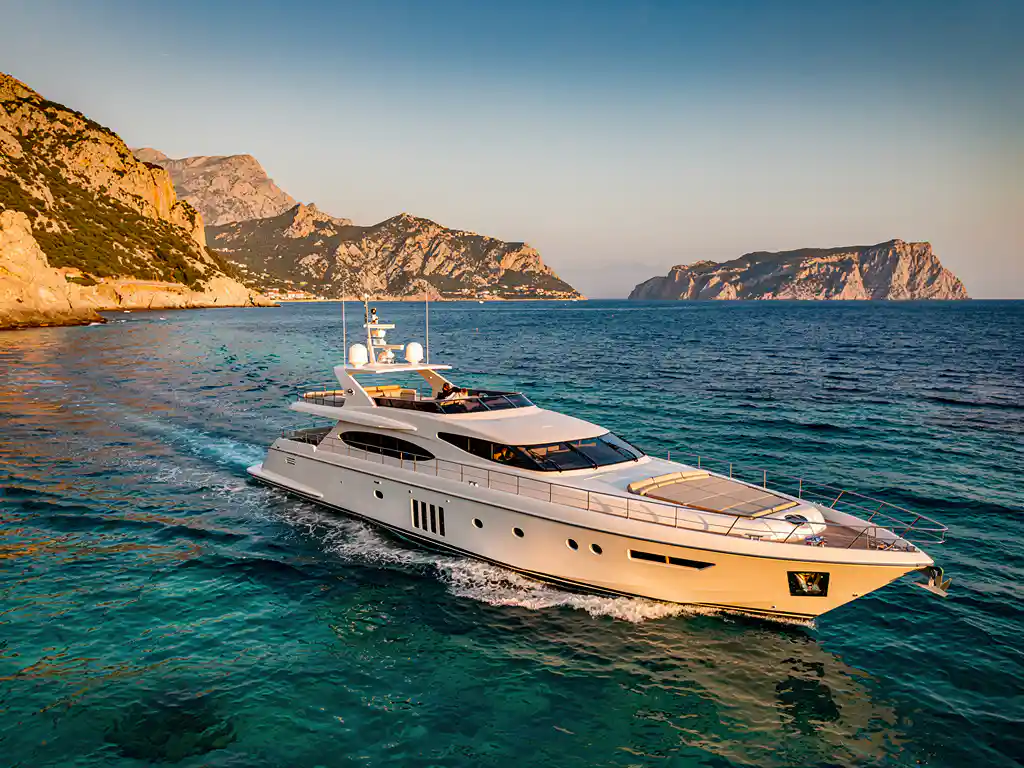 White luxury yacht cruising through turquoise Mediterranean waters between rocky Corsica and Sardinia coastlines at golden hour
